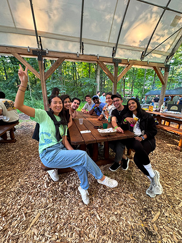 Incoming Simon Business School MBA students smile at a picnic table outdoors.