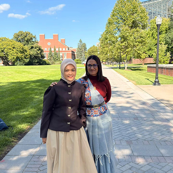 Two members of the 2026 Fulbright Teaching cohort smile on the Wilson Quad in front of LeChase Hall.