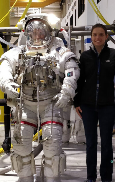 Mary Skow stands next to someone in a full NASA astronaut suit.