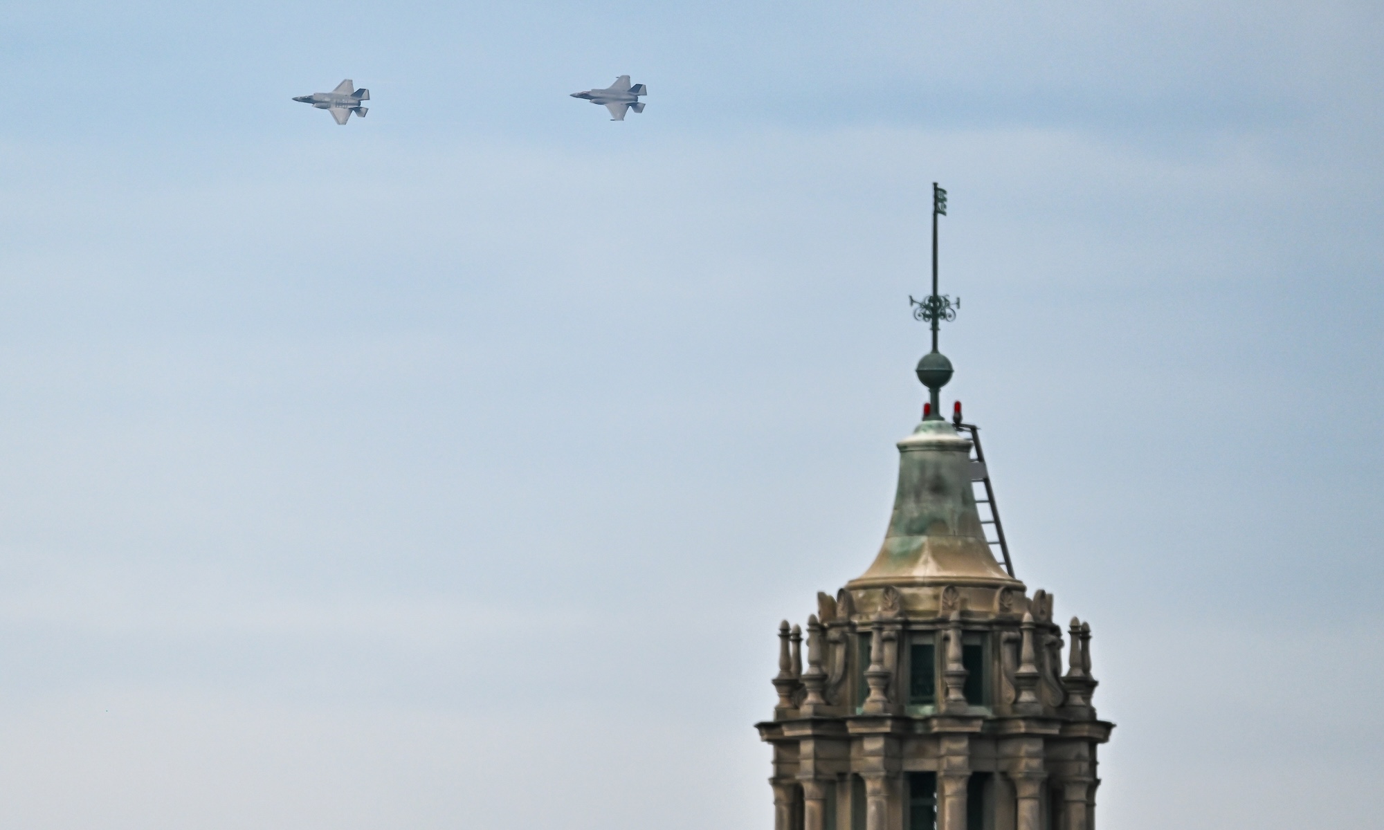 Two US Marine Corps F-35B Lightning II fighter jets, piloted by Major William Horn ’14, left, and Captain Max Miller fly past Rush Rhees Library.