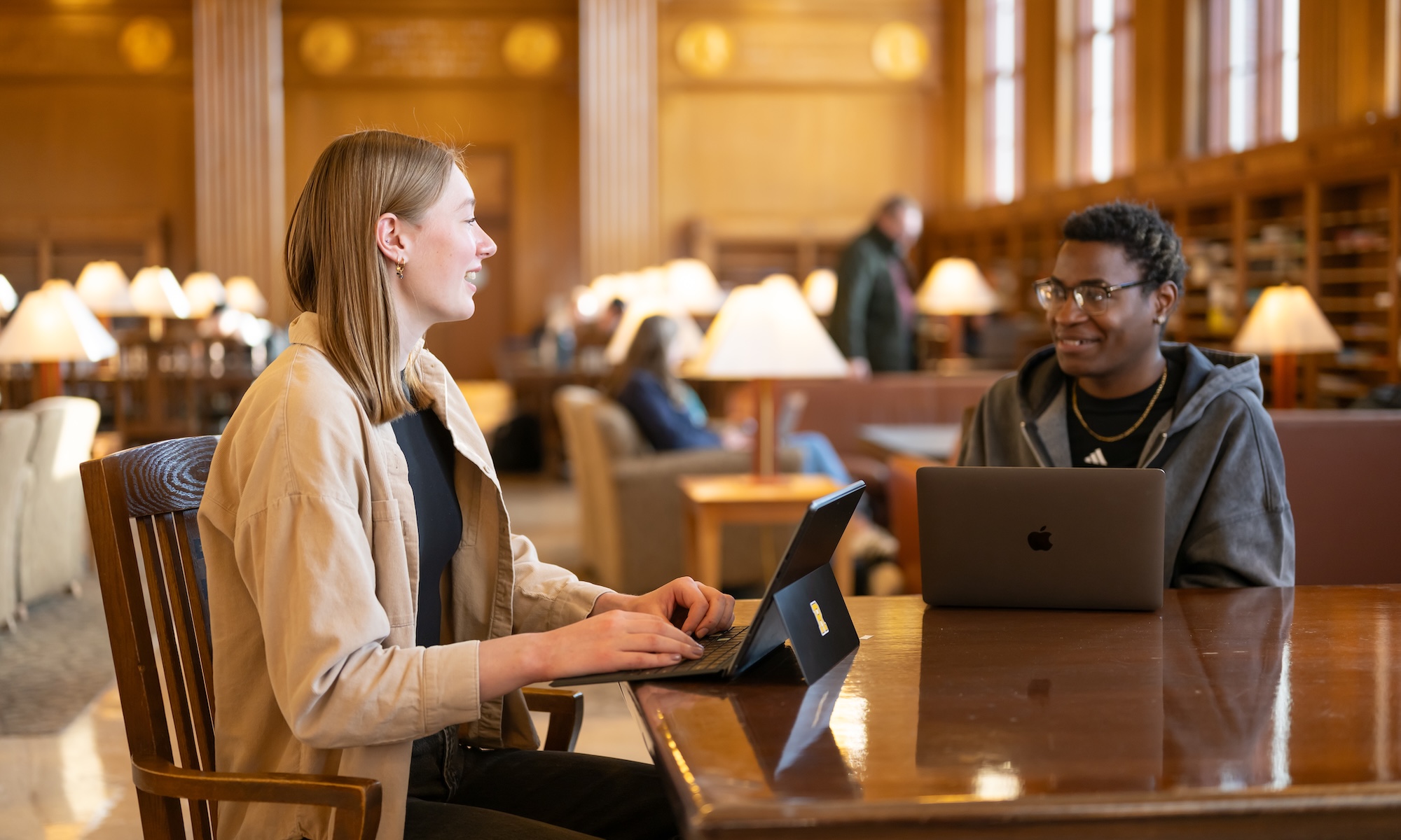 Two students have a discussion in the library.