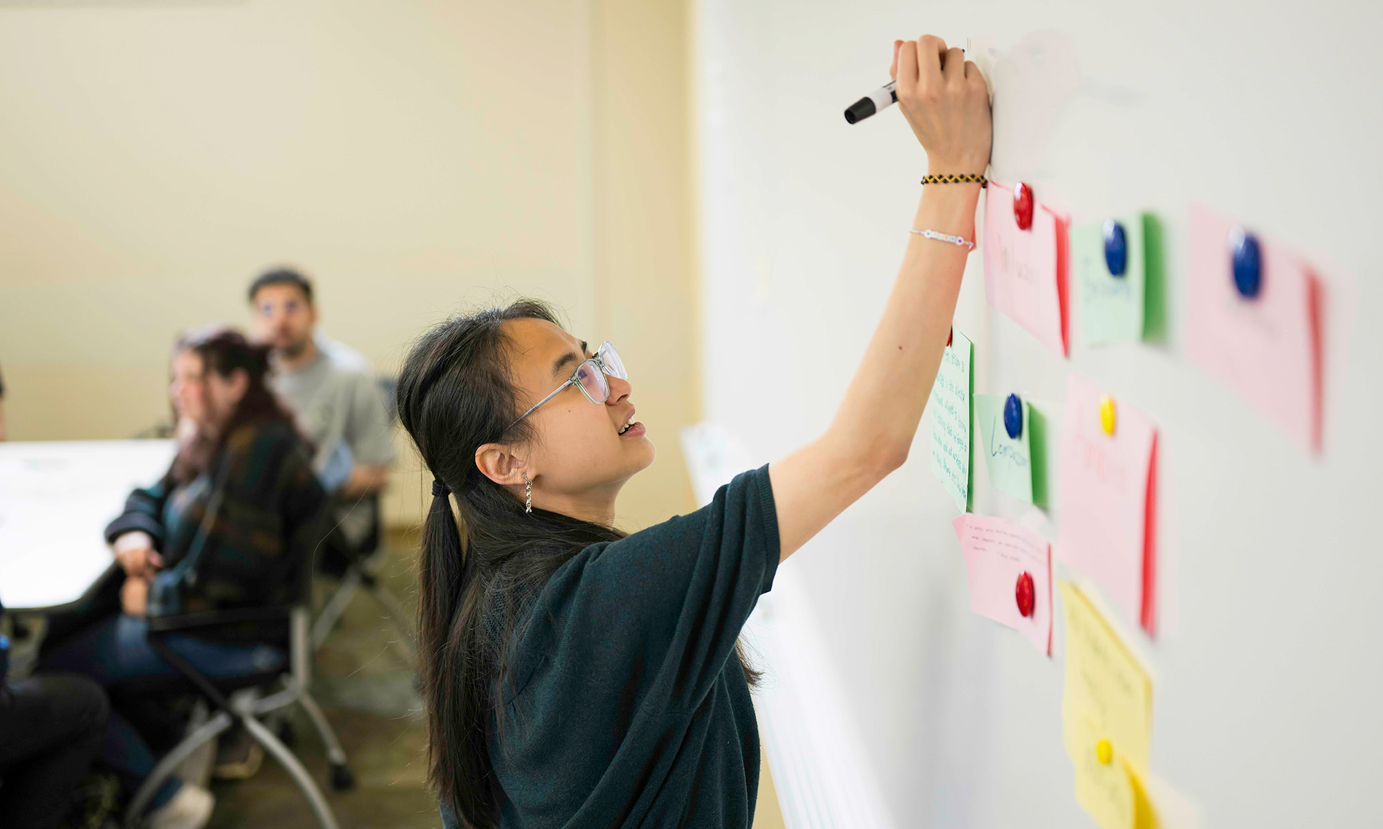 A URochester student models what it means to be a good student by writing on a whiteboard as part of a class assignment.