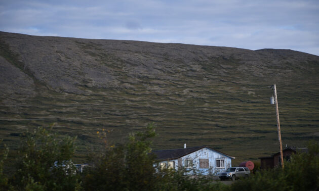 Solifluction-formed wave patterns on an Alaskan hillslope with a house a pickup truck at the base.