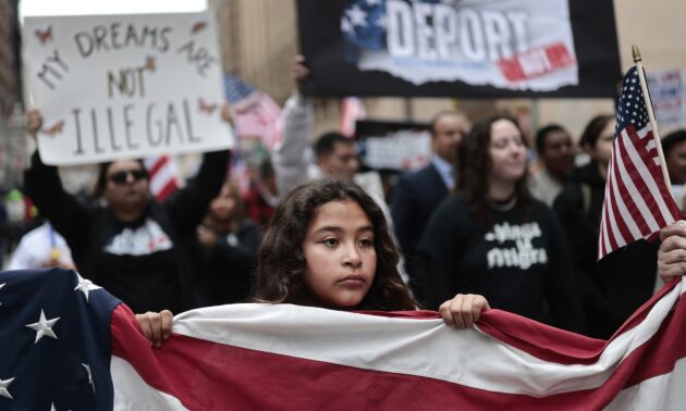 A demonstrator helps carry an American flag as immigrants rights supporters march downtown.
