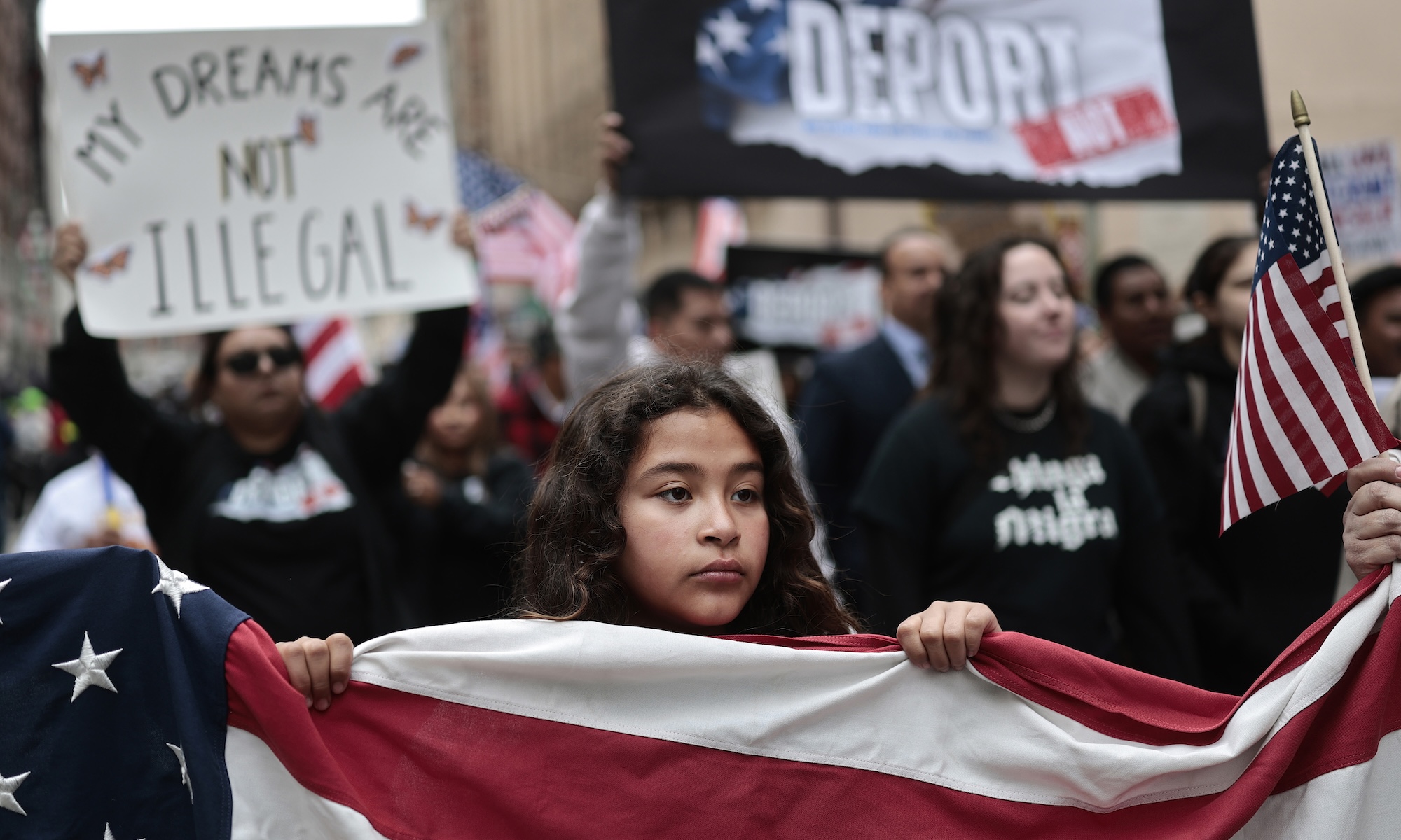 A demonstrator helps carry an American flag as immigrants rights supporters march downtown.