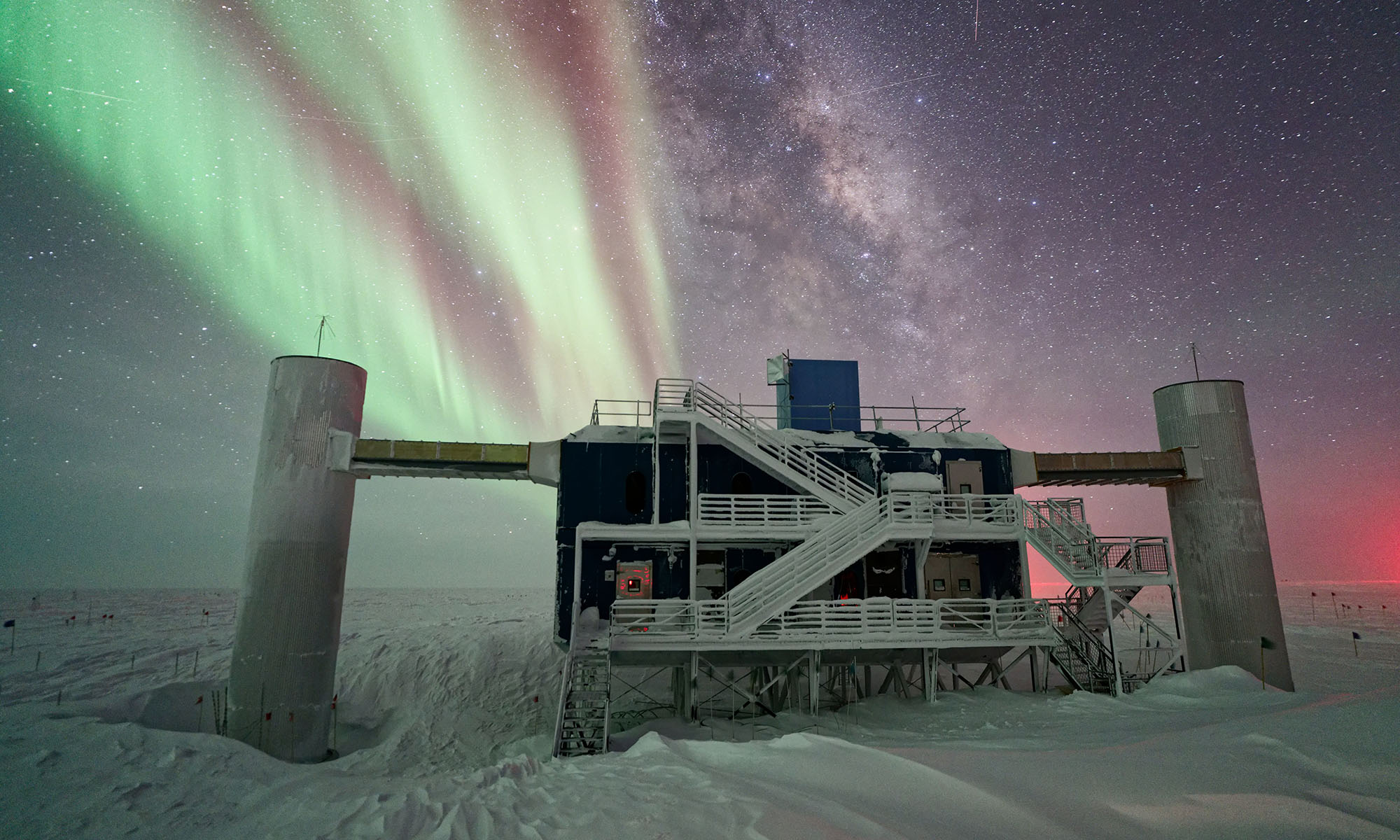 IceCube Neutrino Observatory at night with the Northern Lights in the sky.