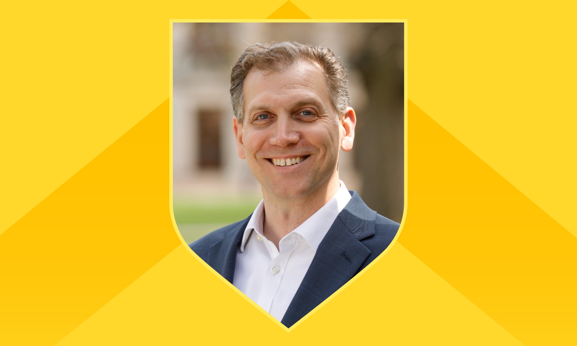 Portrait of Mitch Lovett within a shield outline against a yellow background with a darker yellow chevron on it.