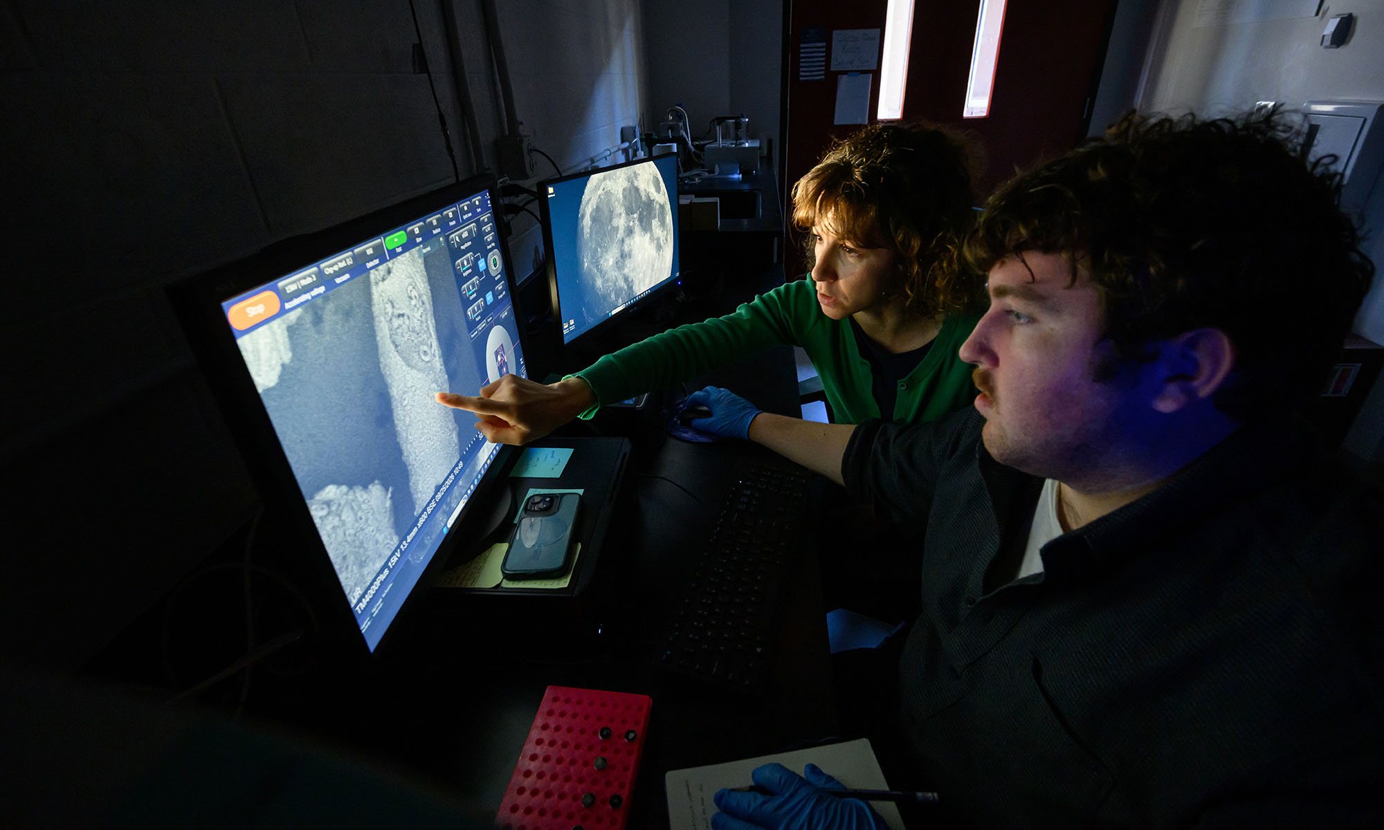Paleoceanographer Chiara Borrelli and graduate student Adrien Trendell in a darkened room examine high-resolution images of foraminifera microfossils.