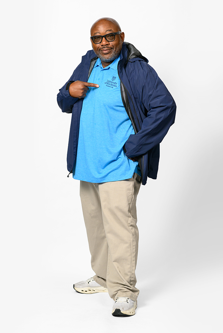 John Blackshear in a bright blue URochester polo, navy blue jacket, khakis, and sneakers.