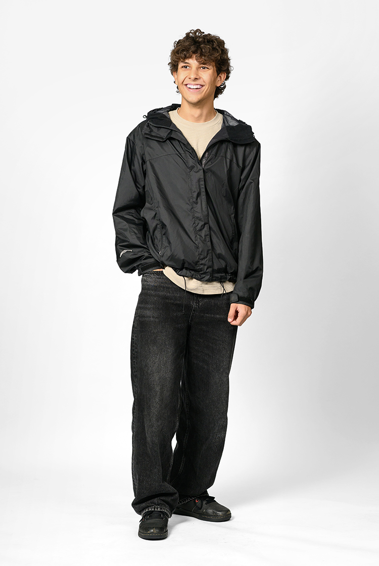 Zinedine Bousraou in a cream-colored shirt, black windbreaker, black jeans, and black shoes.