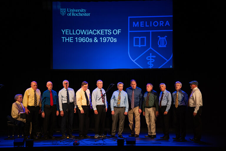 Members of the YellowJackets a cappella group from the 1960s and 70s perform on stage.