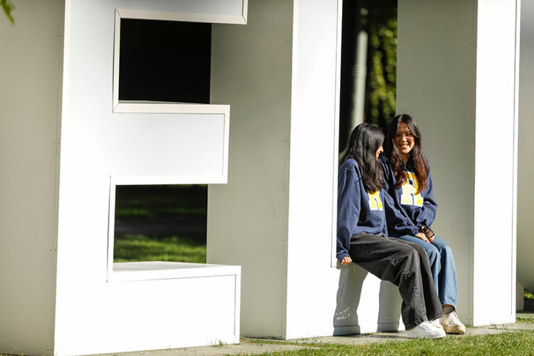 Two undergraduates in their senior year sit on the giant 