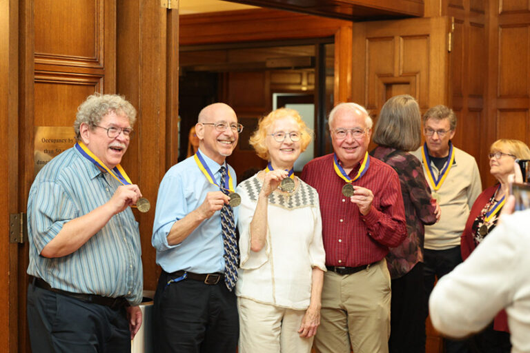 URochester alumni holding up their medals to mark 50 years since graduating.