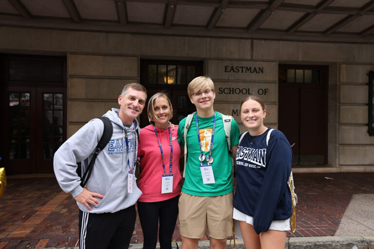Four Meliora Weekend 2026 attendees representing the Eastman School of Music in front of the school's main building.