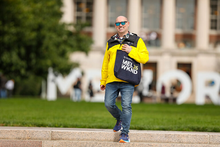 URochester alumnus Alex Vivenzio in head-to-toe yellow and blue gear walks across the Eastman Quad.
