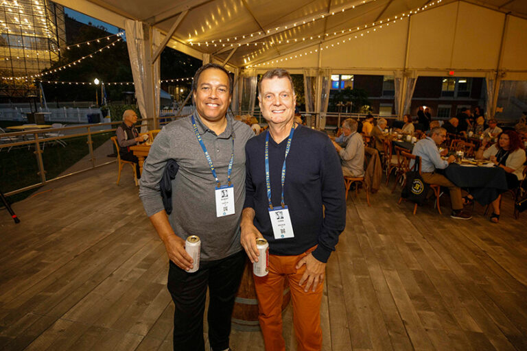 Two Meliora Weekend attendees smile for the camera during the evening festivities under the Meliora Village tent.