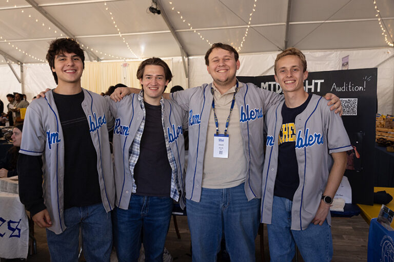 Four young men wearing Midnight Ramblers baseball jerseys smile for the camera.