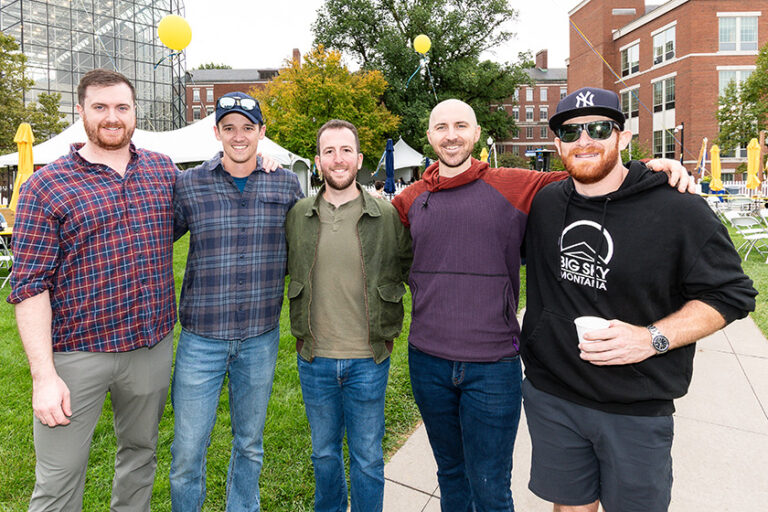 Five male Meliora Weekend attendees pose for a group photo with their arms around each other.