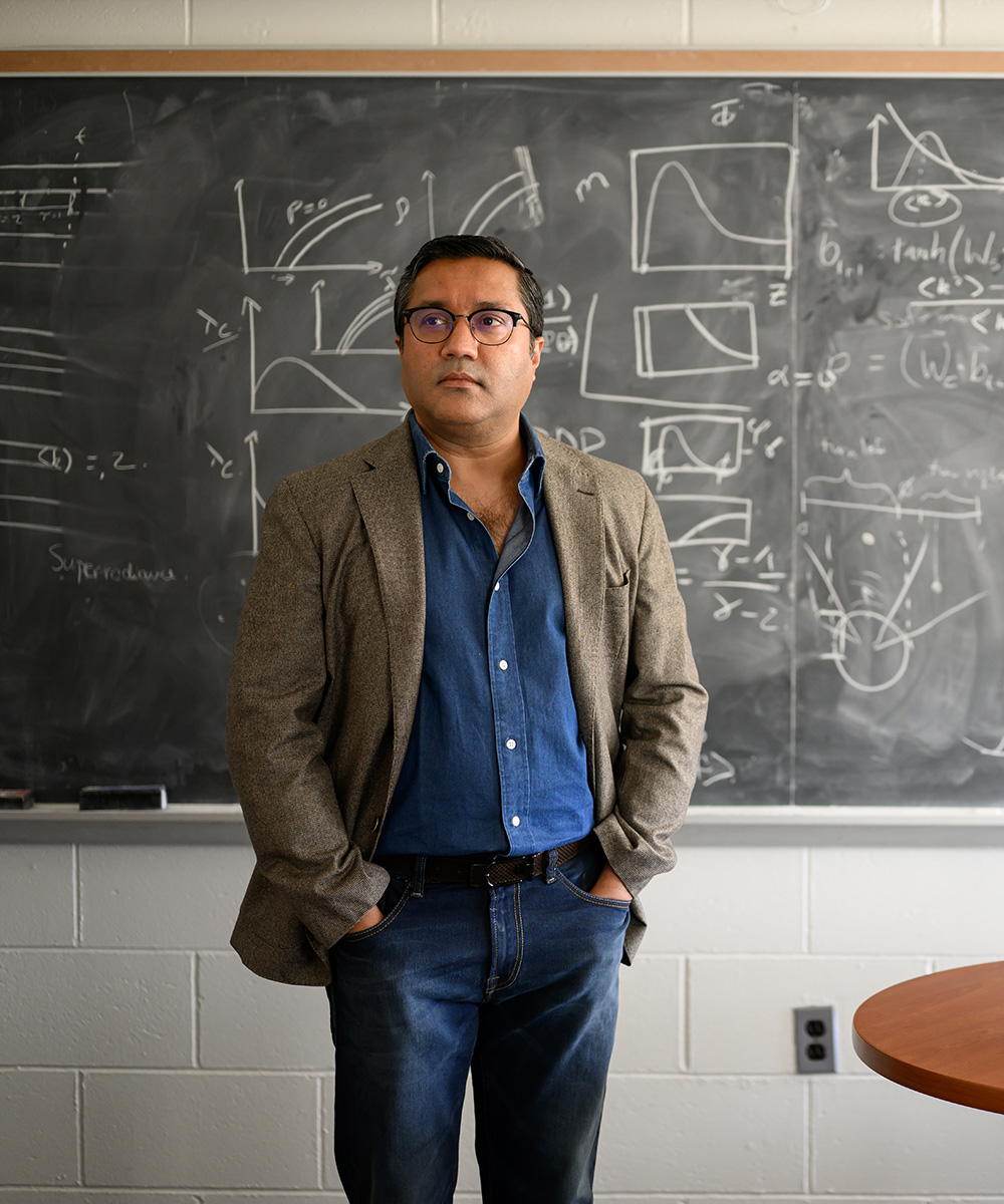 Gourab Ghoshal standing in front of a chalkboard covered with equations.
