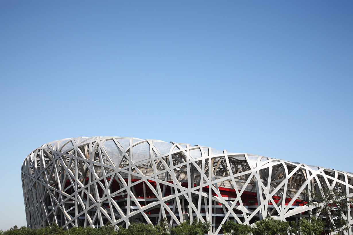 Beijing’s National Stadium, known as the Bird’s Nest, features an interwoven steel exterior beneath a clear blue sky.