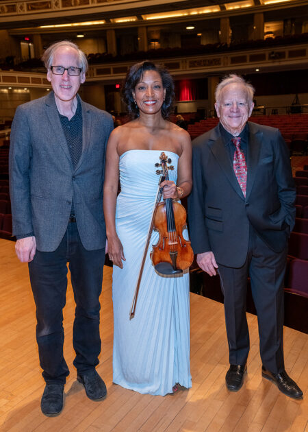 Jeff Beal, violinist Kelly Hall-Tompkins, and conductor Leonard Slatkin pose onstage at Eastman Theatre, with Hall-Tompkins holding her violin.