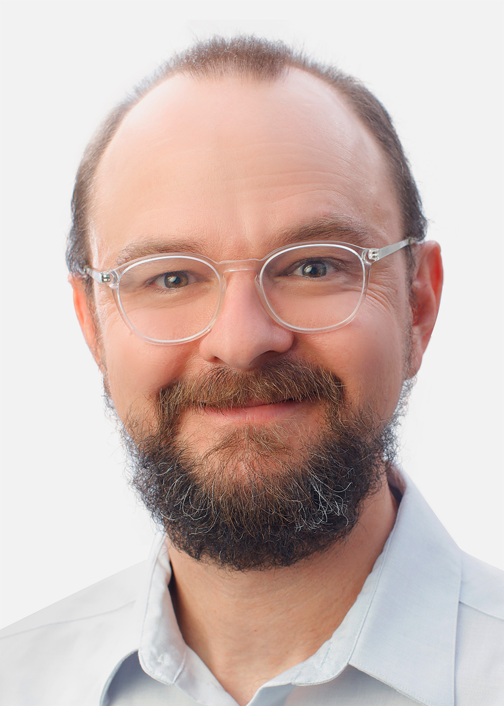 John Kessler smiles in a light-colored shirt against a white background.