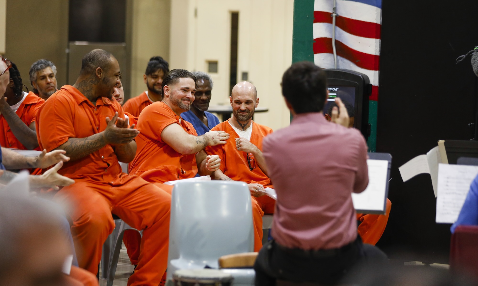 Seated inmates congratulate each other while Eastman School of Music students perform their compositions.