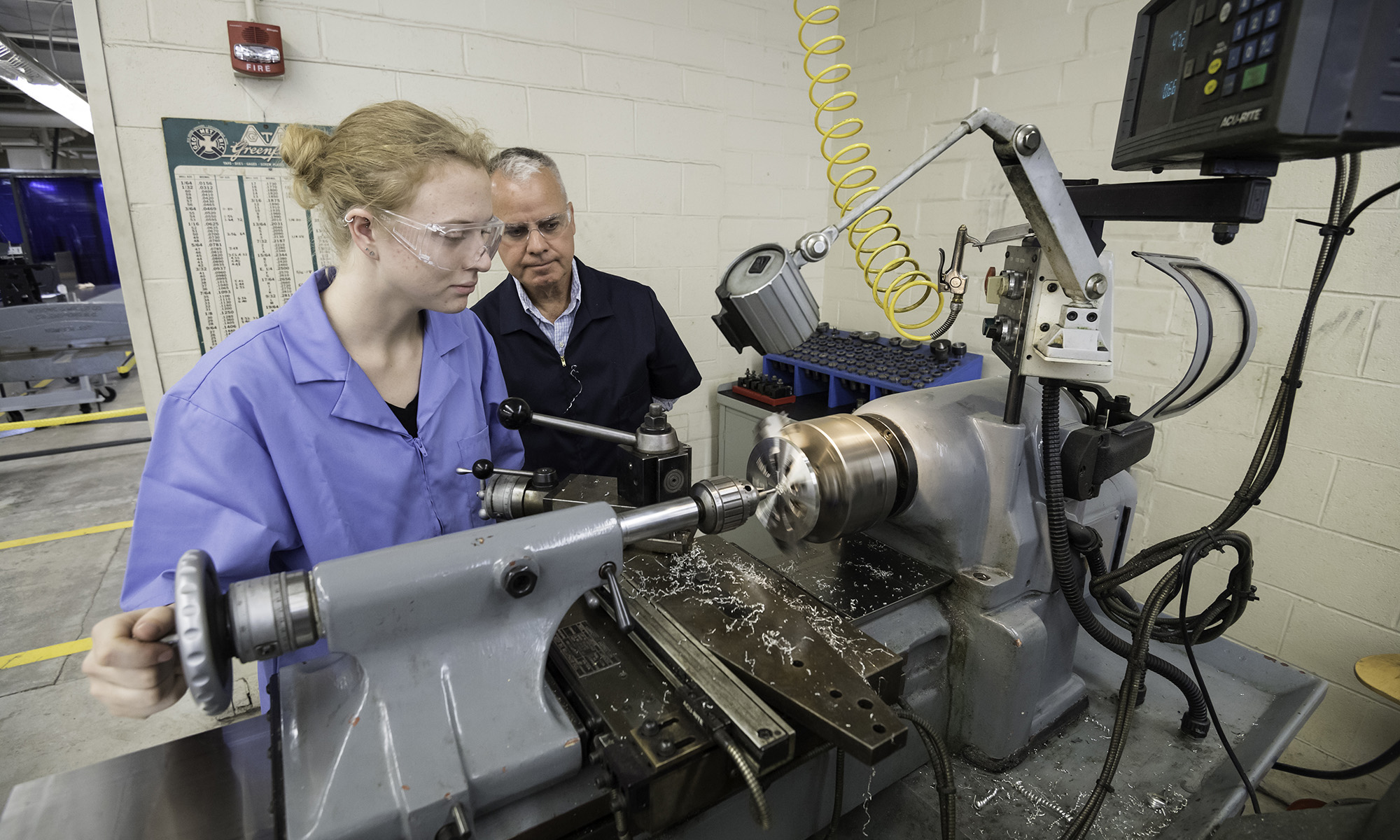 Professor Chris Muir and student Linnea Krall work with a lathe in Taylor Hall.