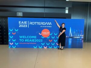Megan Bennett-Spears posing in front of an EAIE 2023 conference sign in Rotterdam