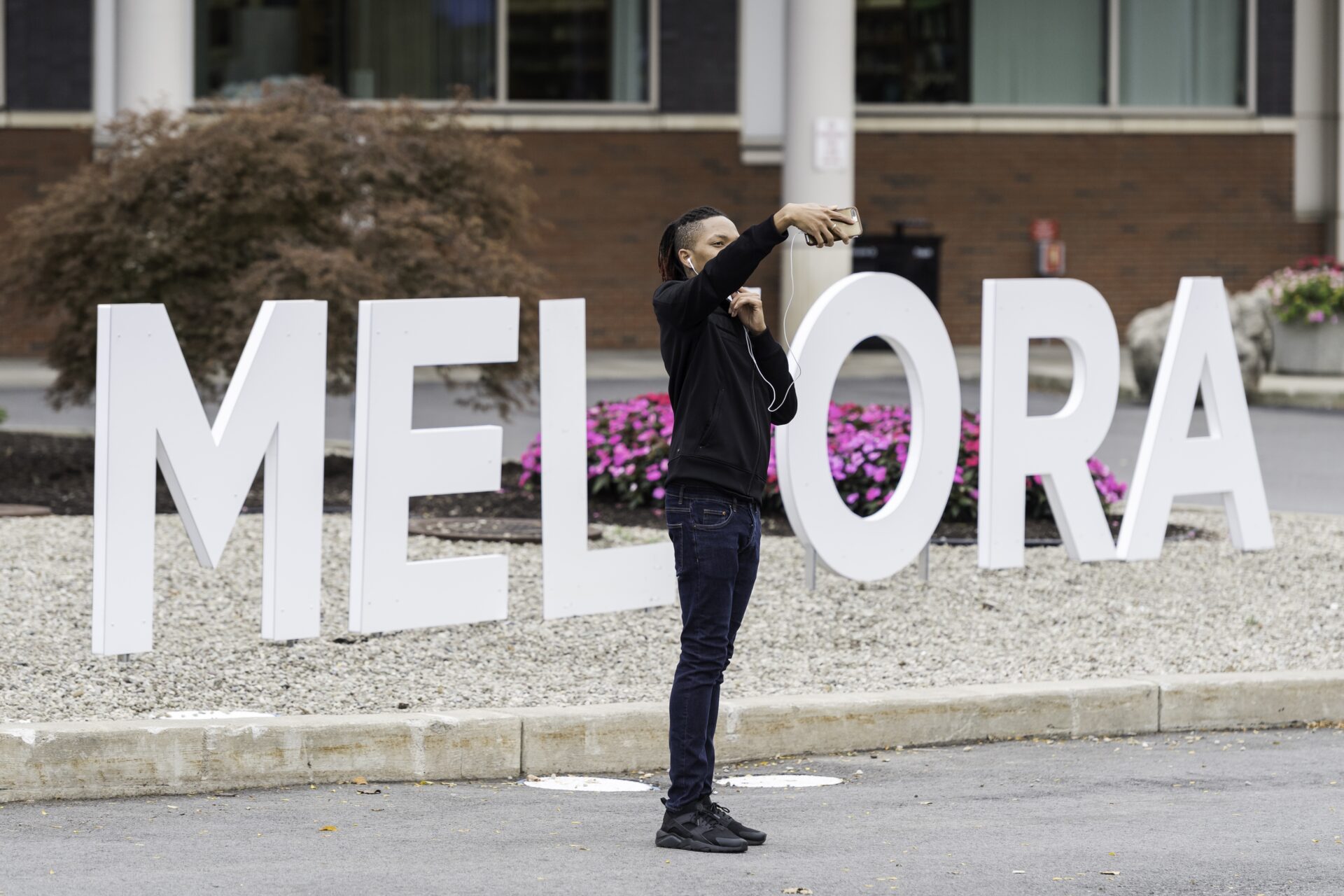 A student taking a selfie with the giant "Meliora" letters