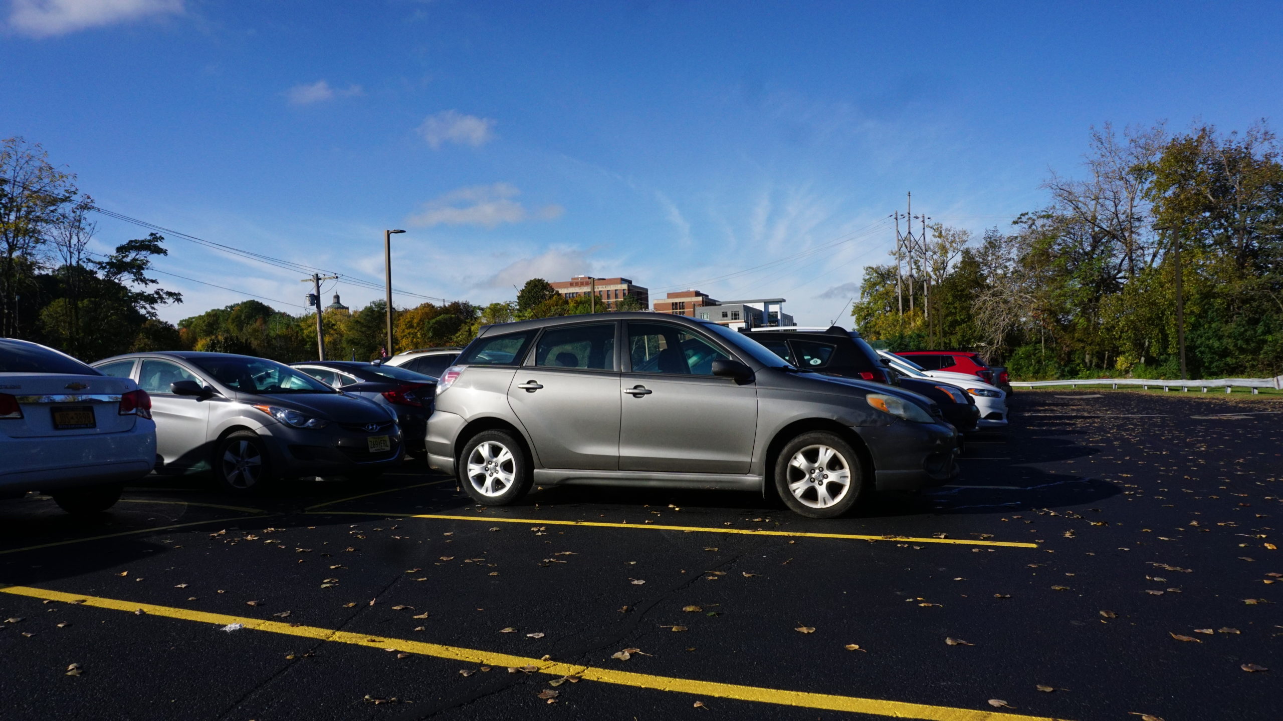 Vehicles parked in University of Rochester lot with brick buildings in background