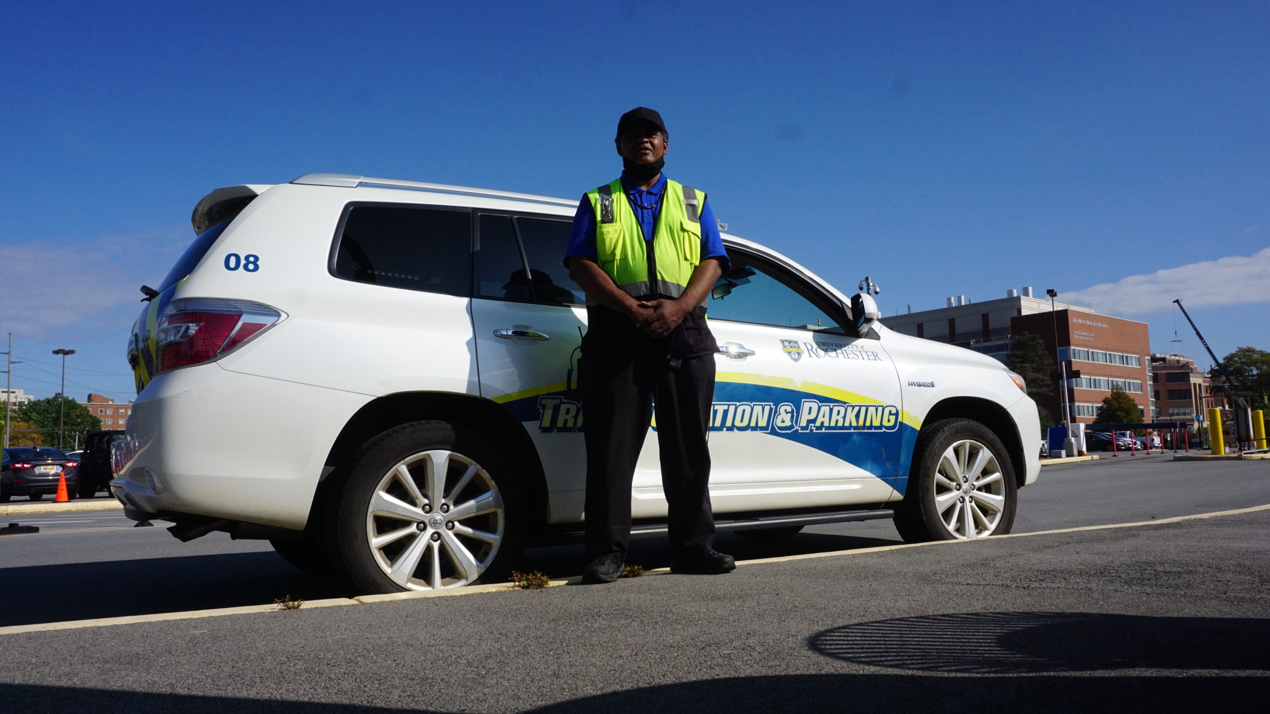 Parking employee standing in front of white Transportation and Parking SUV parked in lot