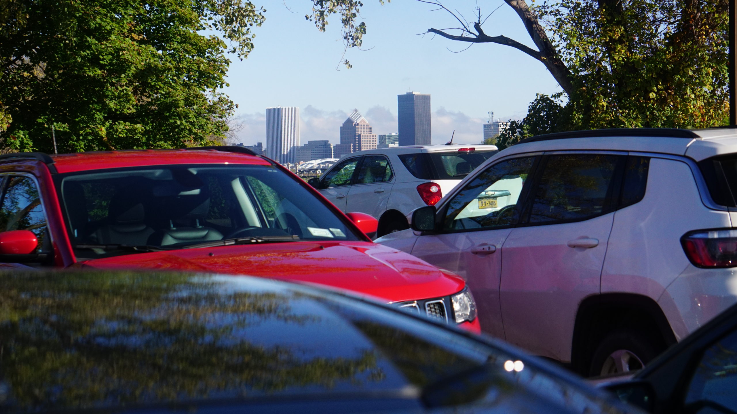 Red and white vehicles parked in lot with Rochester NY skyline in background