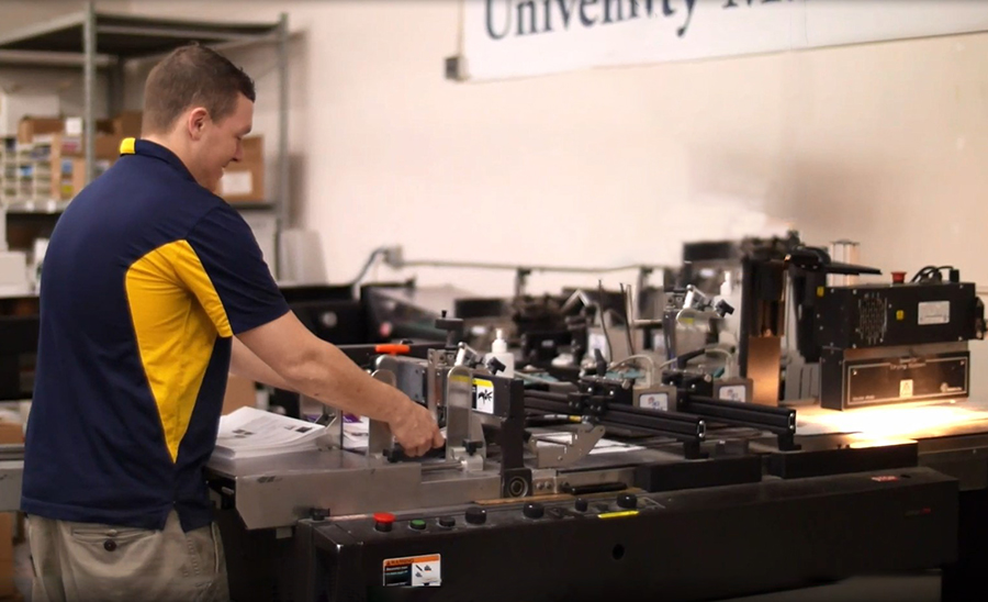 Employee operating bulk mail machine.
