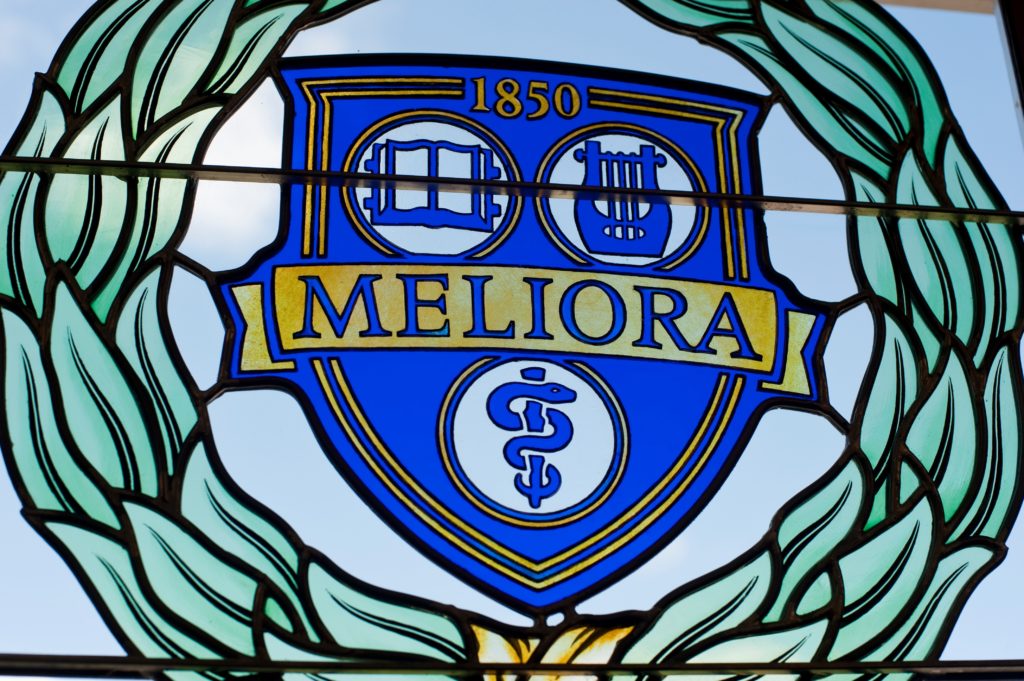 The University of Rochester's Meliora logo and shield insignia in stained glass