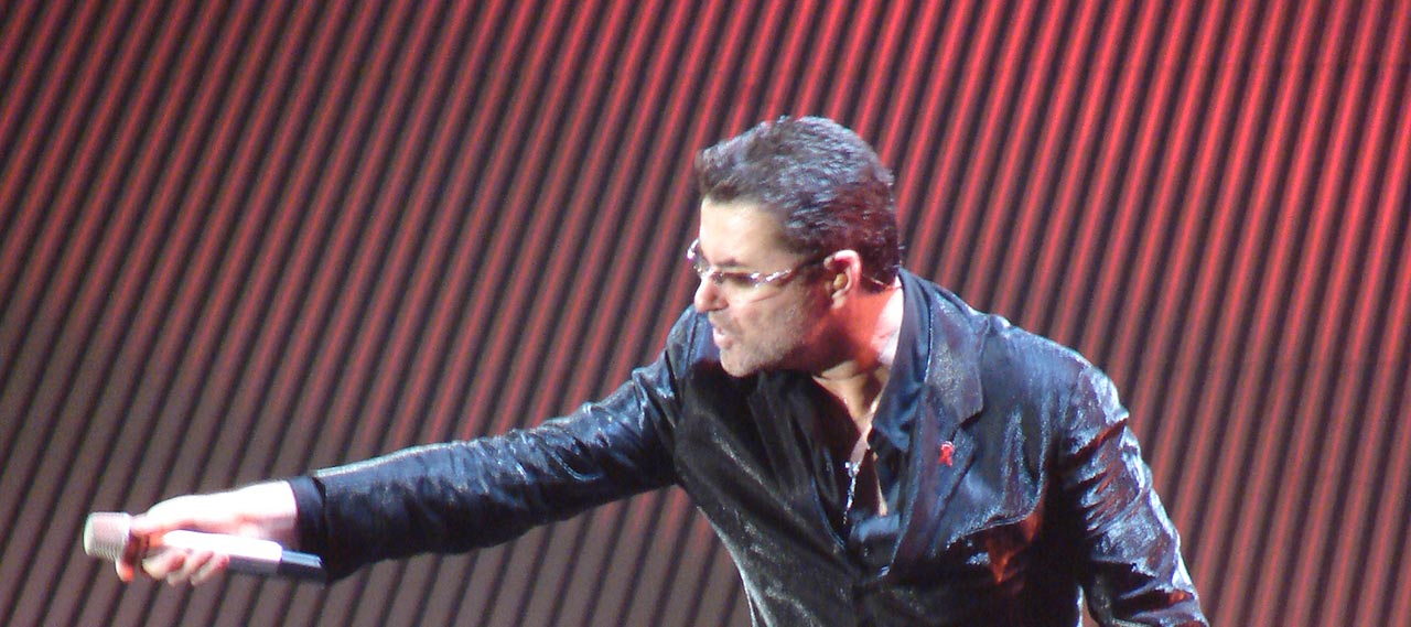 George Michael holding out a microphone.