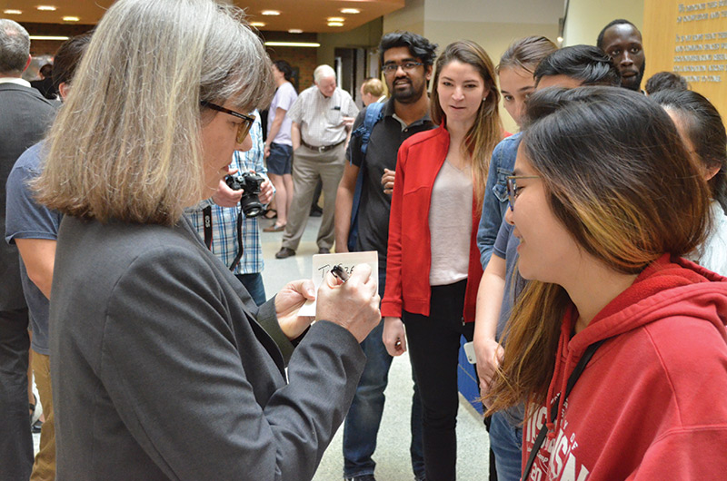 photo of University of Rochester alumnus and Nobel laureate Donna Strickland signing autographs for young people in Munnerlyn Atrium of Goergen Hall