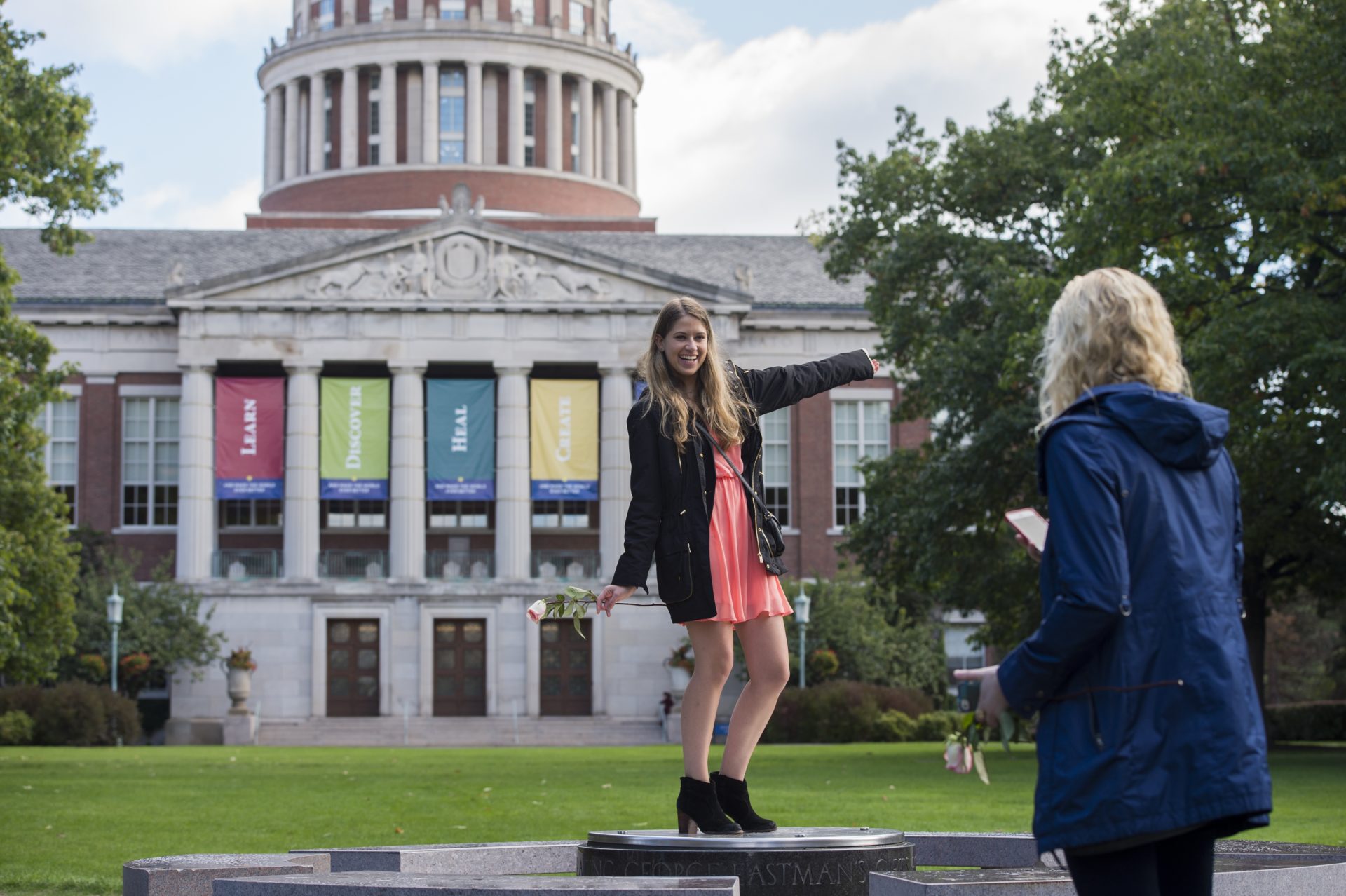 A University of Rochester student posing for a picture in front of the Rush Rhees Library