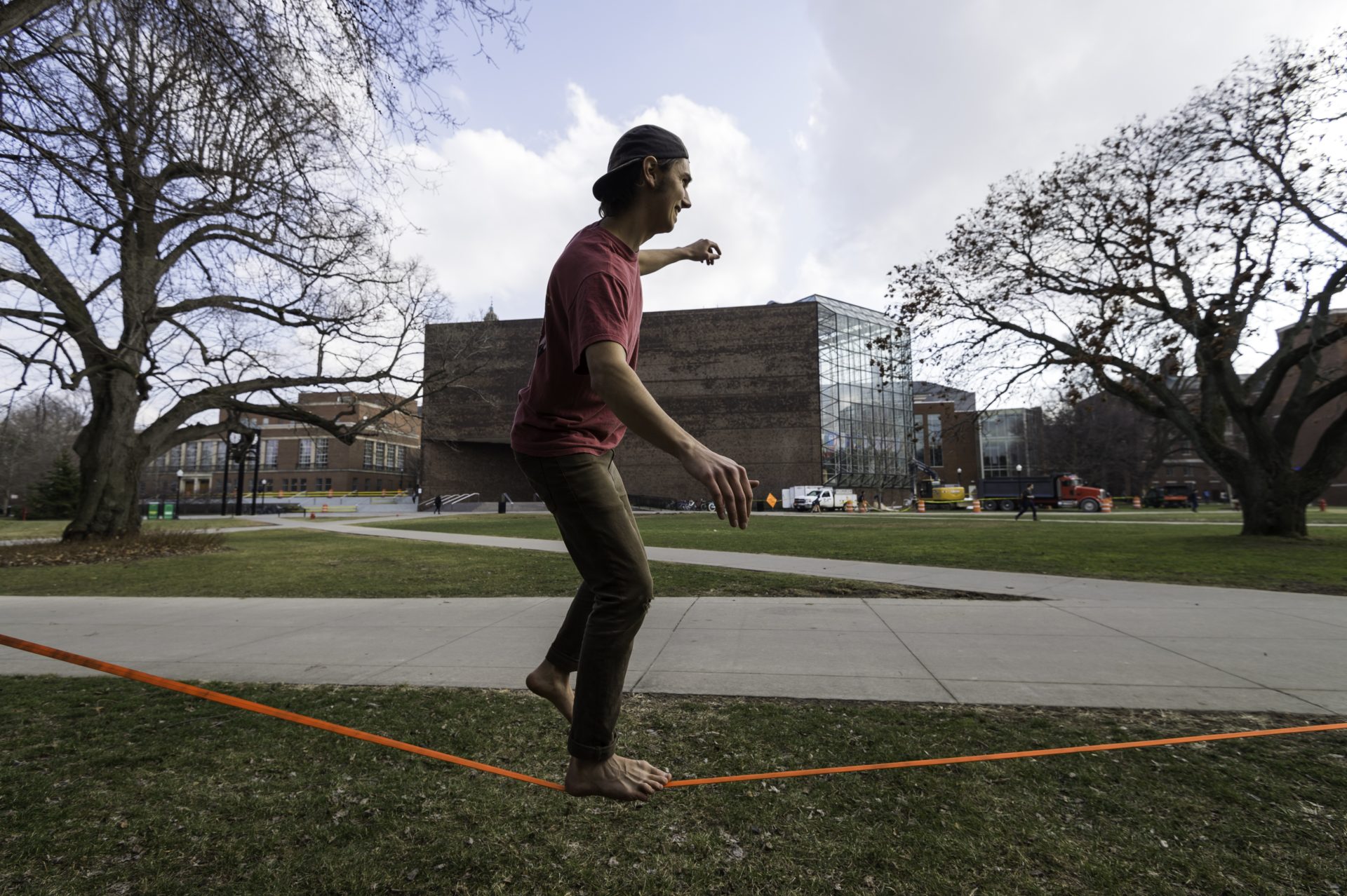A student walking across a tight rope set up on the University of Rochester's campus