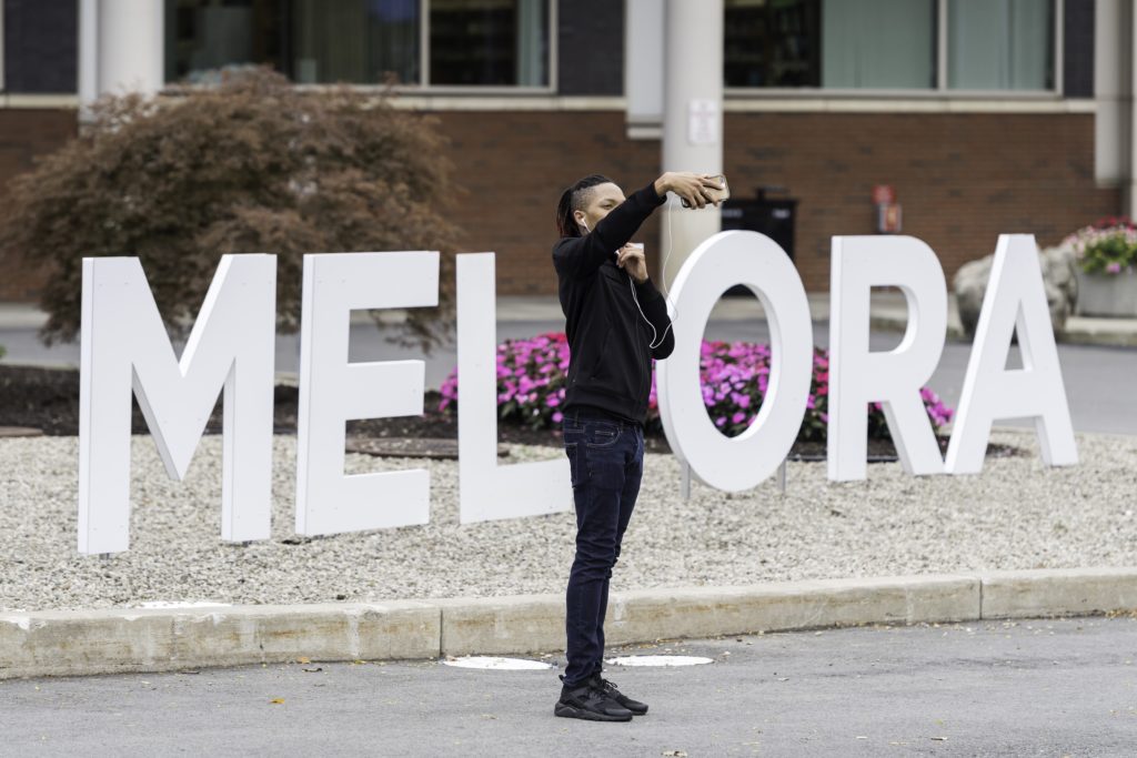 A University of Rochester student taking a selfie in front of a 