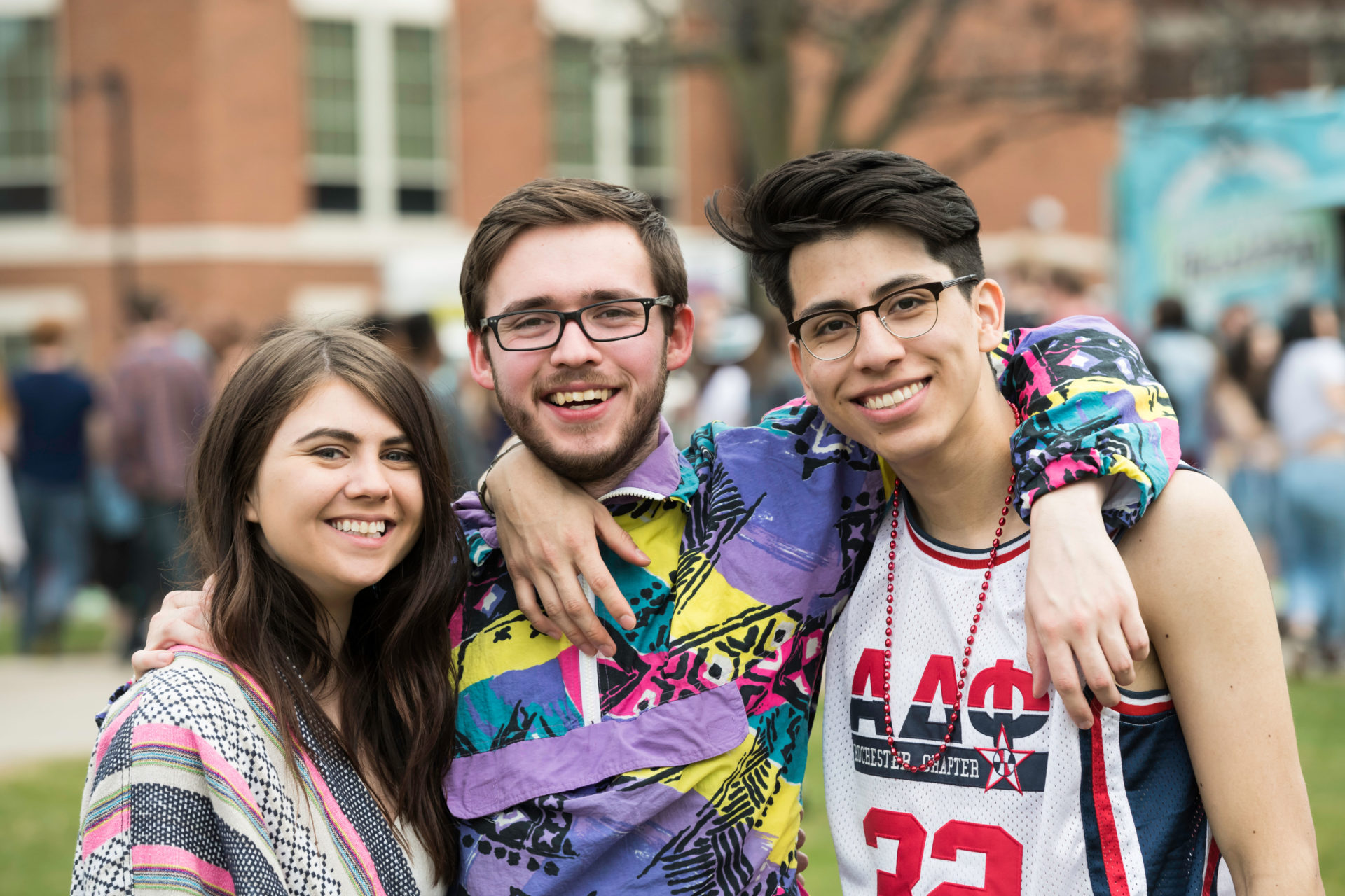 A group of University of Rochester students with their arms around each other, smiling outdoors during Dandelion Day