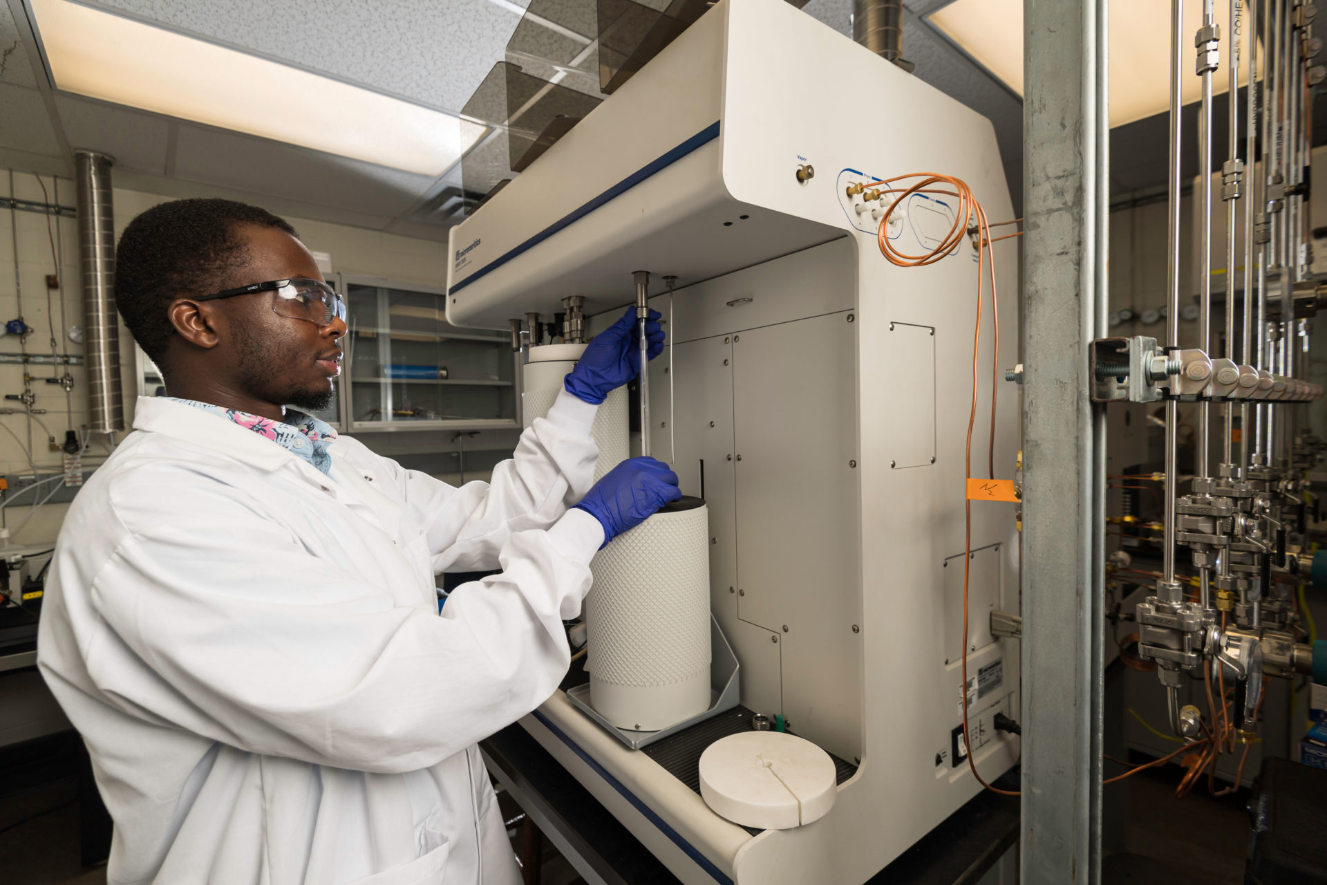 A University of Rochester engineer in a lab, pulling down a tube for processing a test result