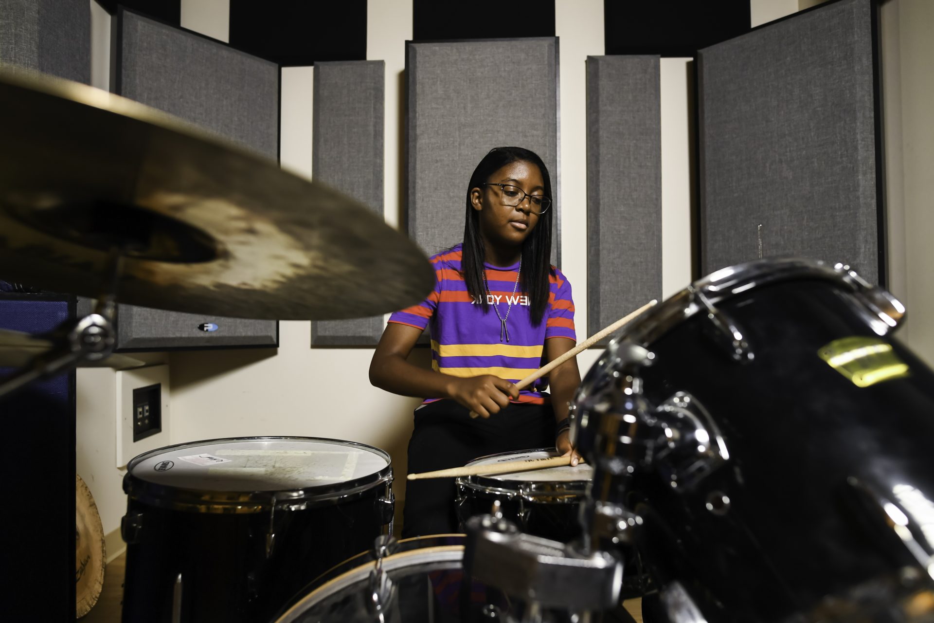 A University of Rochester student playing the drums in a studio