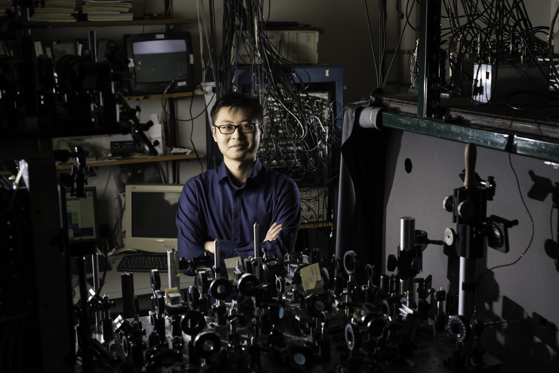 A University of Rochester PhD student in a lab in front of complicated microscope equipment