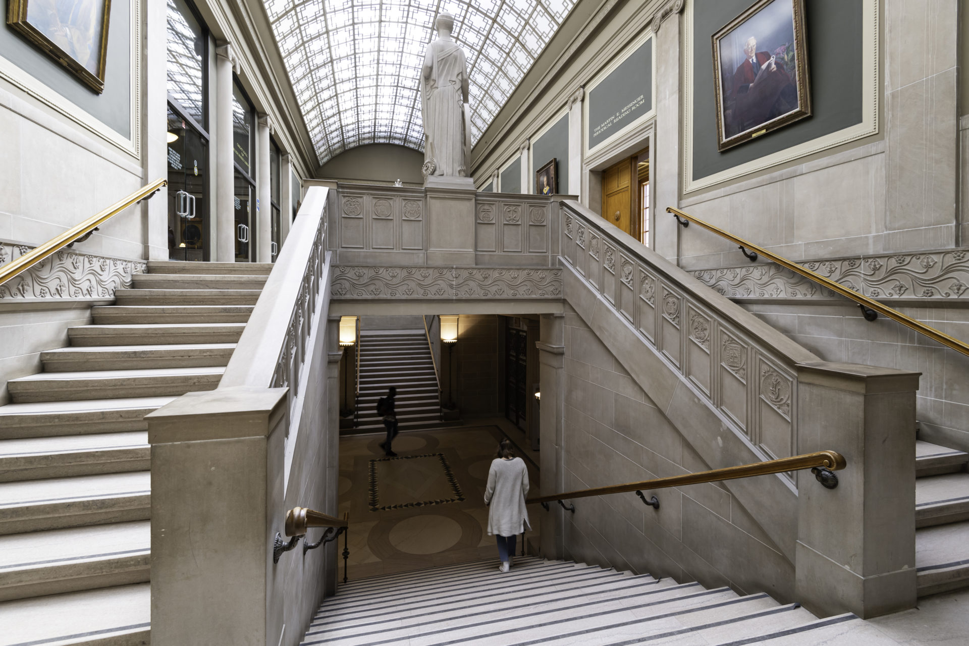 A student walking down a staircase on the University of Rochester's library