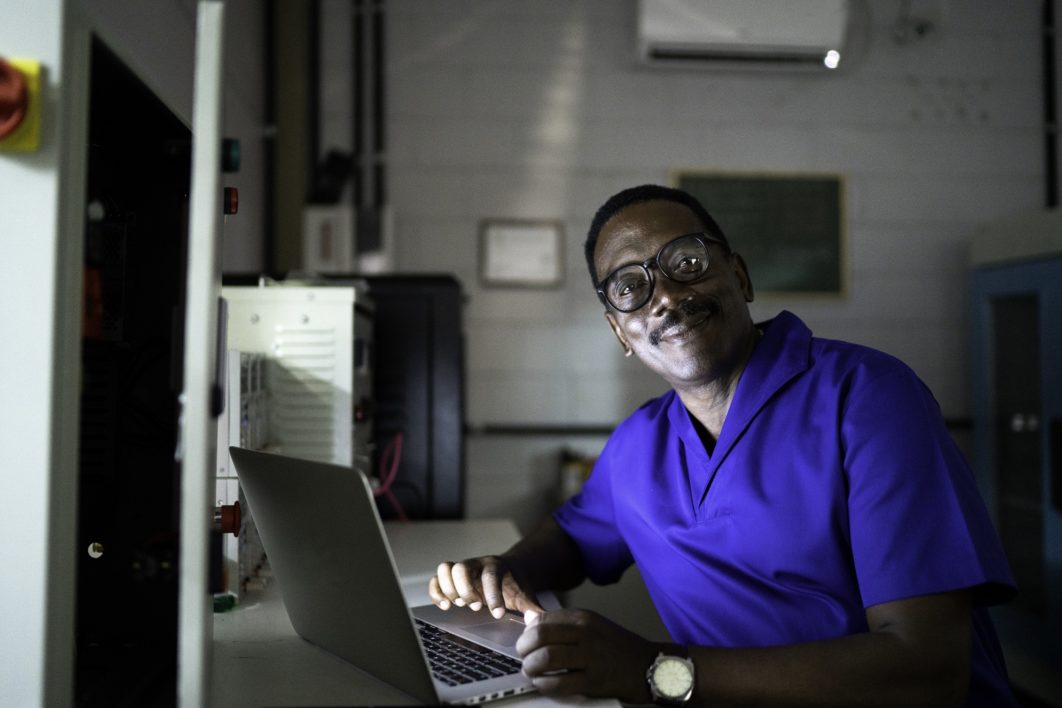 Portrait of man working late and using laptop in industry