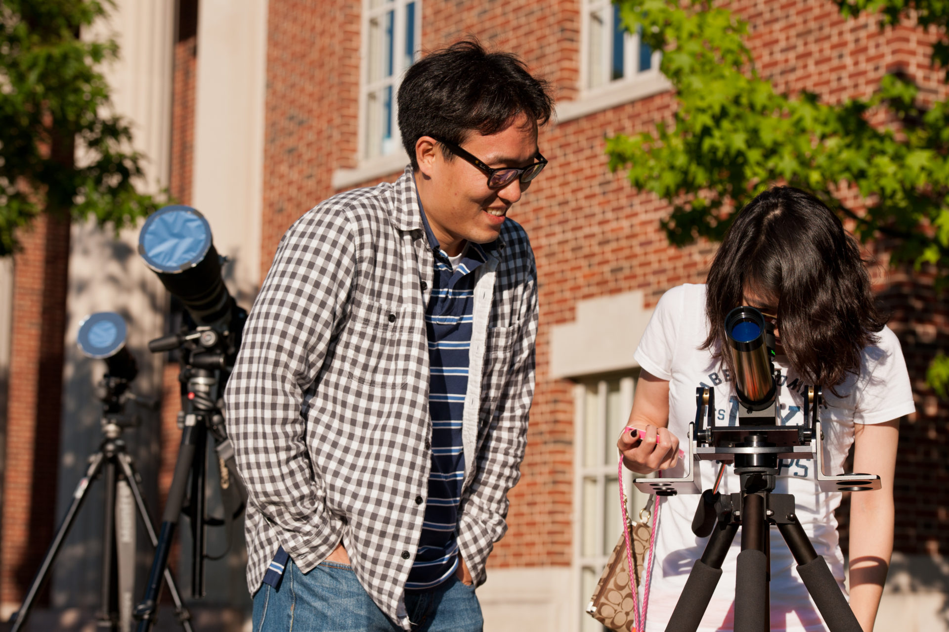 A University of Rochester student looking through a telescope at the sky, with a professor assisting