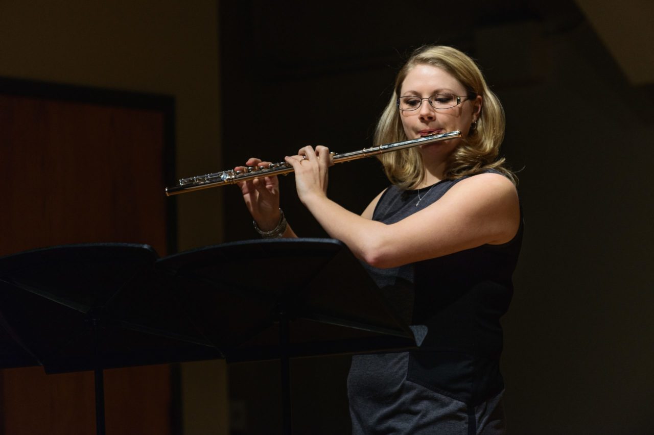 A University of Rochester student playing a flute in front of a crowd