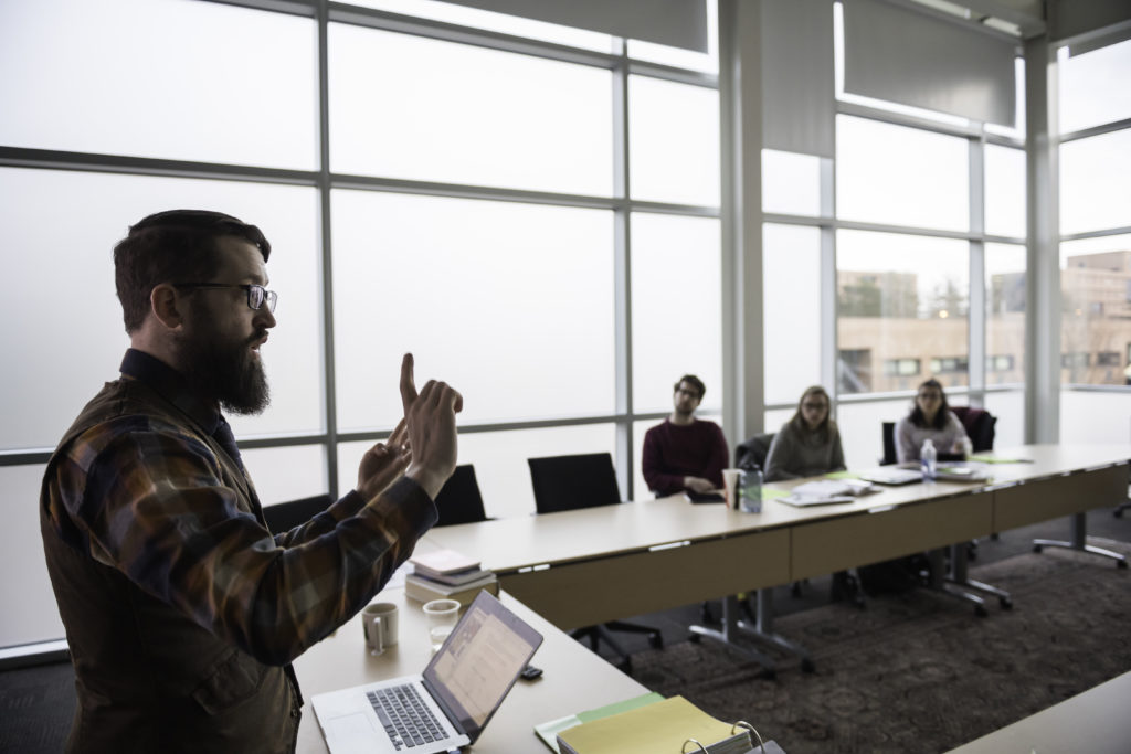 A graduate student teachers in front of a classroom