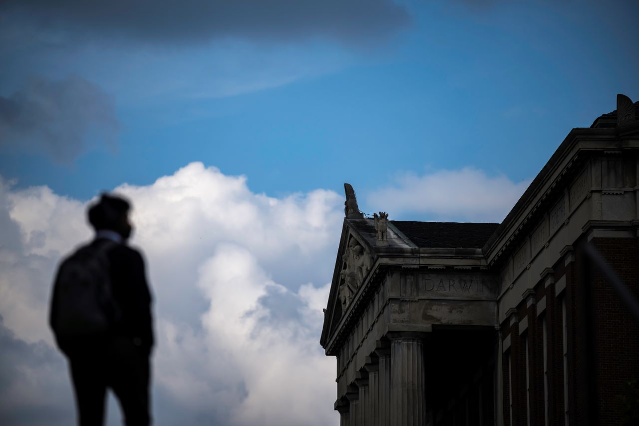 A student silhouette in front of Rush Rhees Library